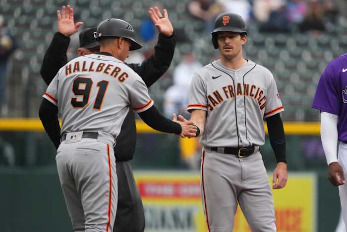 SF Giants outfielder Mike Yastrzemski high-fives third-base coach Mark Hallberg during their game against the Rockies on September 22, 2022.